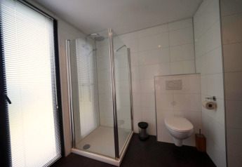 Baño moderno en L-Cube, Spaarnwoude, Países Bajos, con ducha de cristal, inodoro y ventana grande.