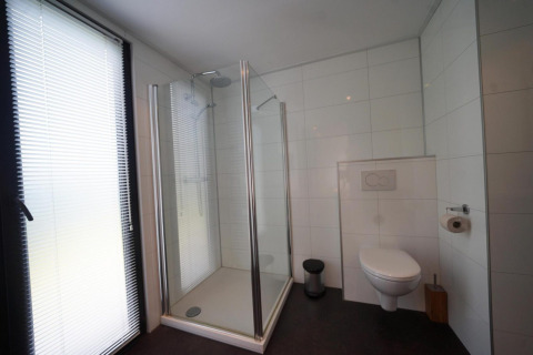Salle de bain moderne au L-Cube à Spaarnwoude, Pays-Bas, avec douche, WC suspendu et grande fenêtre.