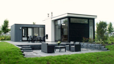 Moderne L-Cube lodge bij Spaarnwoude in Nederland met terras, grote ramen en uitzicht op de tuin.