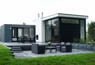 Moderne L-Cube lodge ved Spaarnwoude i Holland med store vinduer, terrasse og have, set udefra.