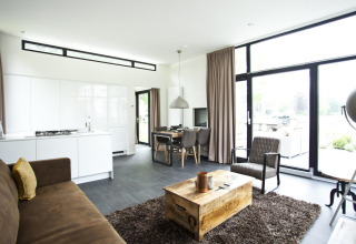 Moderne Lodge Cube Maximaal in Spaarnwoude, Niederlande, mit hellem Wohnraum und großen Fenstern zur Terrasse.