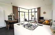 Moderne woonkamer en keuken in een Cube Maximaal lodge in Spaarnwoude, Nederland, met grote ramen.