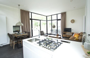 Sala y cocina modernas en una Cube Maximaal lodge en Spaarnwoude, Países Bajos, con ventanas grandes y luz natural.