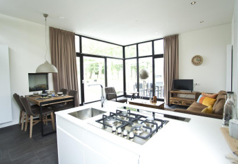 Modernes Wohnzimmer und Küche in einer Cube Maximaal Lodge in Spaarnwoude, Niederlande, mit großen Fenstern.