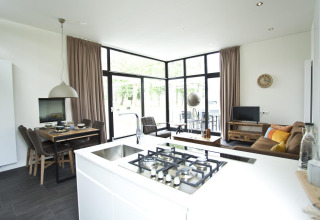 Sala y cocina modernas en una Cube Maximaal lodge en Spaarnwoude, Países Bajos, con ventanas grandes y luz natural.