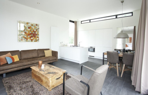 Moderne lodge Cube Maximaal in Spaarnwoude, Nederland, met woonkamer, open keuken en eethoek.