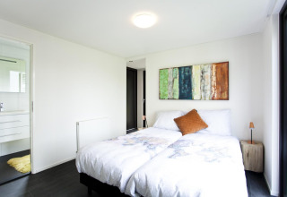 Moderne slaapkamer in de Cube Maximaal-lodge in Spaarnwoude, Nederland, met tweepersoonsbed en wanddecoratie.