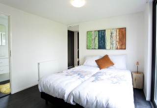 Lichte slaapkamer in de Cube Maximaal-lodge in Spaarnwoude, Nederland, met modern interieur en tweepersoonsbed.