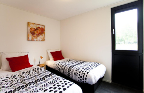 Slaapkamer in Cube Maximaal lodge in Spaarnwoude, Nederland, met twee eenpersoonsbedden en kunst aan de muur.