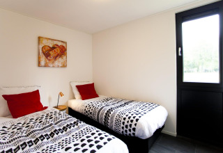 Slaapkamer in Cube Maximaal lodge in Spaarnwoude, Nederland, met twee eenpersoonsbedden en kunst aan de muur.