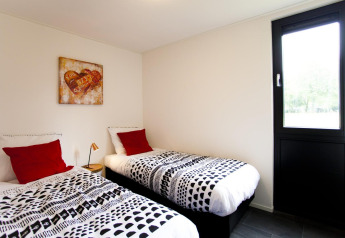 Slaapkamer in Cube Maximaal lodge in Spaarnwoude, Nederland, met twee eenpersoonsbedden en kunst aan de muur.