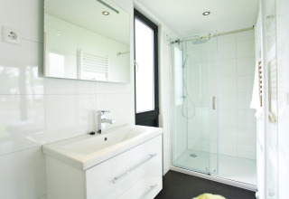 Moderne badkamer in Cube Maximaal lodge te Spaarnwoude, Nederland, met douche en grote spiegel.