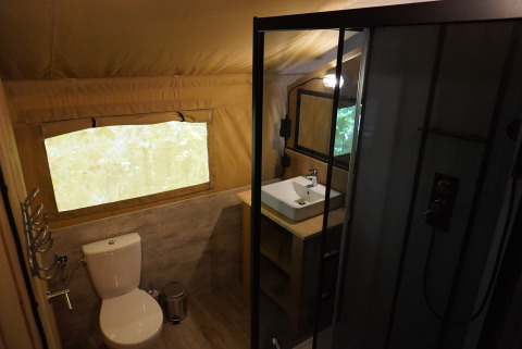 Salle de bain moderne dans une tente safari avec toilettes, lavabo et douche au Camping Pittoresque en France.