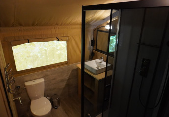 Moderne badkamer in een safaritent met toilet, wastafel en douche bij Camping Pittoresque in Frankrijk.