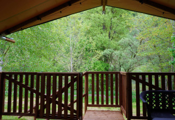 Vista dalla veranda di una tenda safari al Camping Pittoresque in Francia, con una foresta verde sullo sfondo.