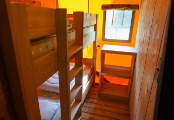 Interno di tenda safari al Camping Pittoresque in Francia con letti a castello e pavimento in legno.