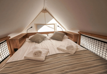 Lit double et serviettes dans une tente Glamping à Reestervallei, Pays-Bas, ambiance chaleureuse.