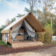 Safari telt med overdækket terrasse og havemøbler, omgivet af natur og træer, ideel til glamping.
