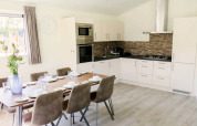 Cuisine moderne et salle à manger d'une lodge Velthorst à De Wije Werelt, Pays-Bas, avec table dressée.