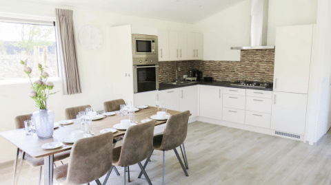 Cocina moderna y comedor en una lodge Velthorst de De Wije Werelt, Países Bajos, con mesa puesta elegante.