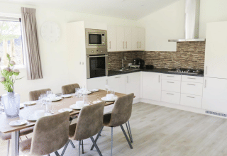 Cuisine moderne et salle à manger d'une lodge Velthorst à De Wije Werelt, Pays-Bas, avec table dressée.