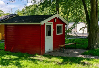 Cabaña de madera roja con puerta blanca y banco, situada en el Het Amsterdamse Bos, Países Bajos.