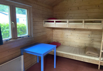 Interior de una cabaña de madera con literas, mesa azul y ventana en Cabin at Het Amsterdamse Bos, Países Bajos.