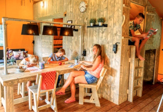 Famille profitant de moments ensemble dans un hébergement glamping chaleureux avec meubles en bois.