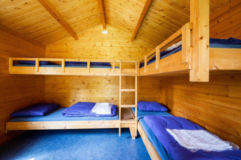 Acogedora cabaña de madera con literas y ropa de cama azul, perfecta para una experiencia glamping.