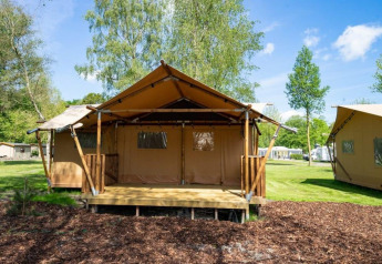 Tente safari Glampingtent au Het Amsterdamse Bos, Pays-Bas, située sur un terrain de camping verdoyant.