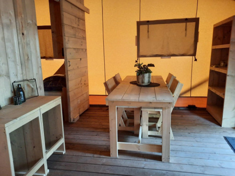 Interior de una Glampingtent en Het Amsterdamse Bos, Países Bajos, con muebles de madera y decoración acogedora.