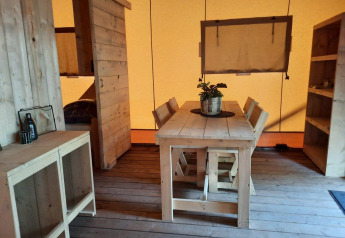 Intérieur d'une Glampingtent au Het Amsterdamse Bos, Pays-Bas, avec meubles en bois et ambiance chaleureuse.