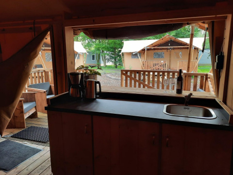 Interior de una tienda safari Glampingtent en Het Amsterdamse Bos, Países Bajos, con vista a la cocina.