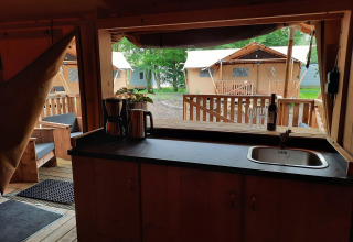 Interior de una tienda safari Glampingtent en Het Amsterdamse Bos, Países Bajos, con vista a la cocina.