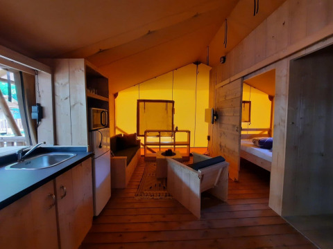 Interior de una tienda safari Glampingtent en Het Amsterdamse Bos, Países Bajos, con cocina y sala.