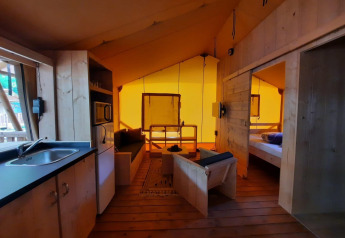 Intérieur d'une tente safari Glampingtent à Het Amsterdamse Bos, Pays-Bas, avec cuisine et salon.