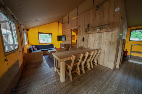 Intérieur d’une Glampingtent lodge à Het Amsterdamse Bos, Pays-Bas, avec mobilier en bois et coin salon chaleureux.