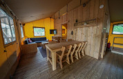 Innenraum eines Glampingtent-Lodges im Het Amsterdamse Bos, Niederlande, mit Holzinterieur und Sitzgruppe.