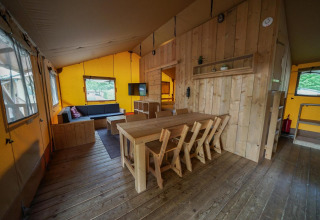 Intérieur d’une Glampingtent lodge à Het Amsterdamse Bos, Pays-Bas, avec mobilier en bois et coin salon chaleureux.