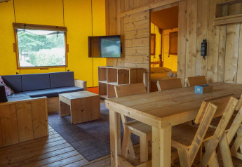 Innenraum einer Glampingtent-Lodge im Het Amsterdamse Bos, Niederlande, mit Holzmöbeln und Wohnbereich.