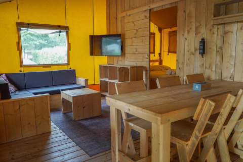 Interior de una tienda Glampingtent en Het Amsterdamse Bos, Países Bajos, con muebles y zona de estar de madera.