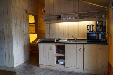 Acogedora cocina de madera en Glampingtent, Het Amsterdamse Bos, Países Bajos, equipada con microondas.