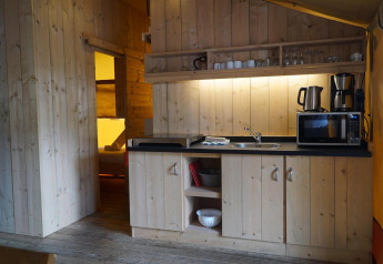 Gemütliche Holzküche in einer Glampingtent-Lodge im Het Amsterdamse Bos, Niederlande, mit Geräten.