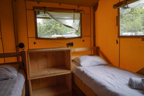 Indvendigt billede af to enkeltsenge i Glampingtent ved Het Amsterdamse Bos, Holland, med træmøbler.