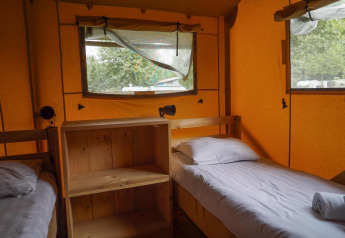 Interieur van twee eenpersoonsbedden en houten kast in Glampingtent bij Het Amsterdamse Bos, Nederland.