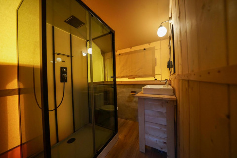 Badezimmer in einem Glampingtent im Het Amsterdamse Bos, Niederlande, mit moderner Dusche und Holzwänden.