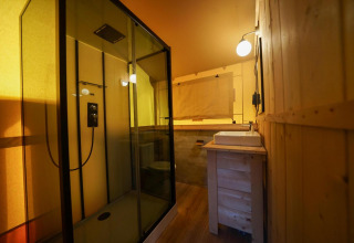 Badeværelse i en Glampingtent ved Het Amsterdamse Bos, Holland, med moderne bruser og trævægge.