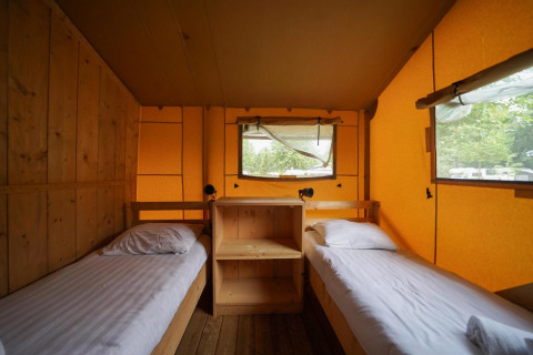 Vista interior de una glampingtent acogedora con dos camas individuales en Het Amsterdamse Bos, Países Bajos.
