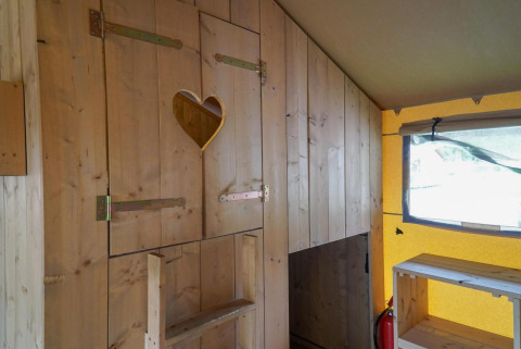 Vista interior de una tienda glamping de madera con un recorte en forma de corazón en Het Amsterdamse Bos.