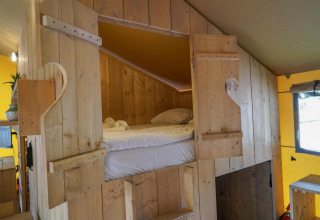 Zona notte accogliente in una Glampingtent presso Het Amsterdamse Bos nei Paesi Bassi con pareti in legno.